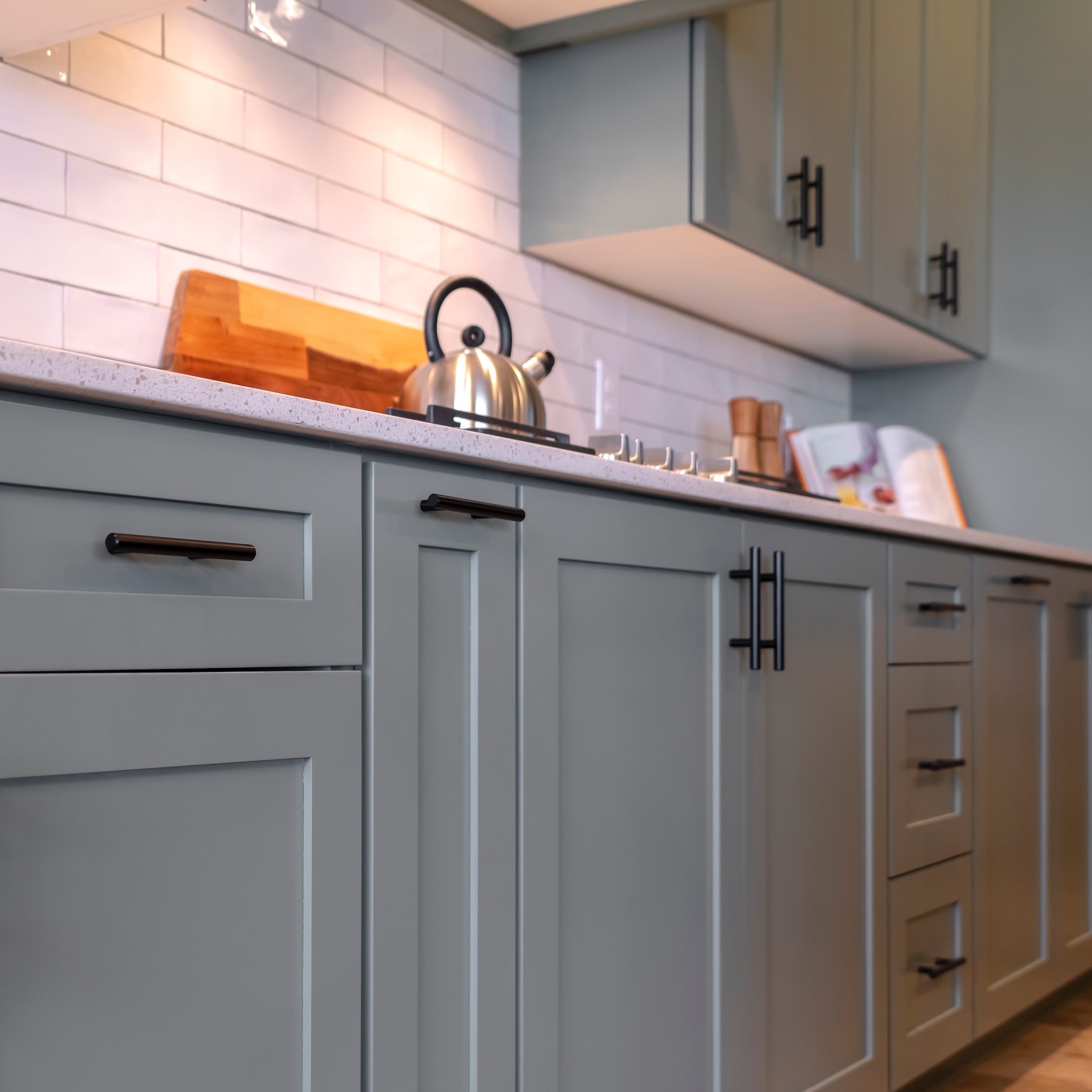 Photo Square Kitchen cabinets with white countertop black handles and tile backsplash