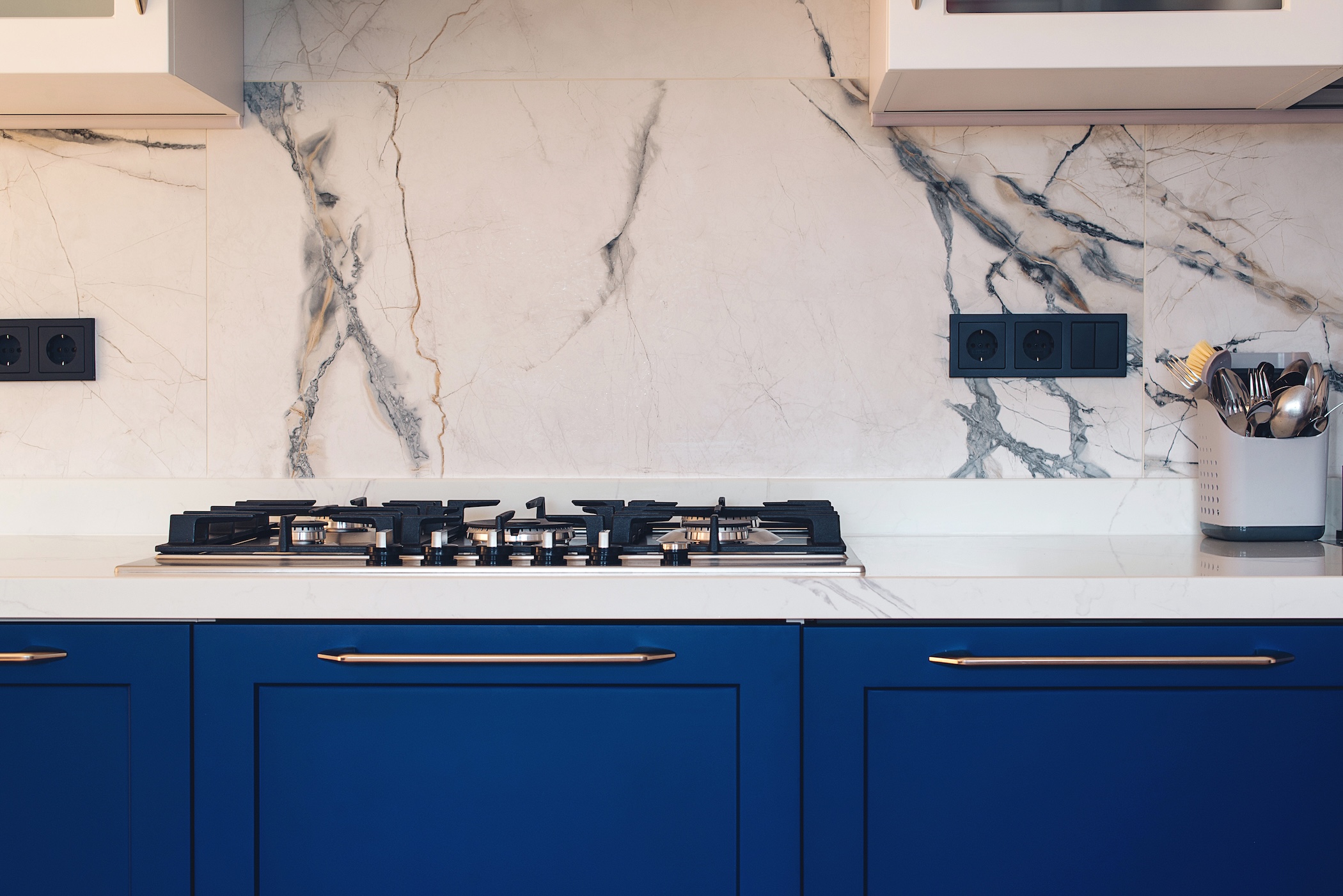 Modern kitchen clean interior design. Modern luxury gas stove top with tiled backsplash.
