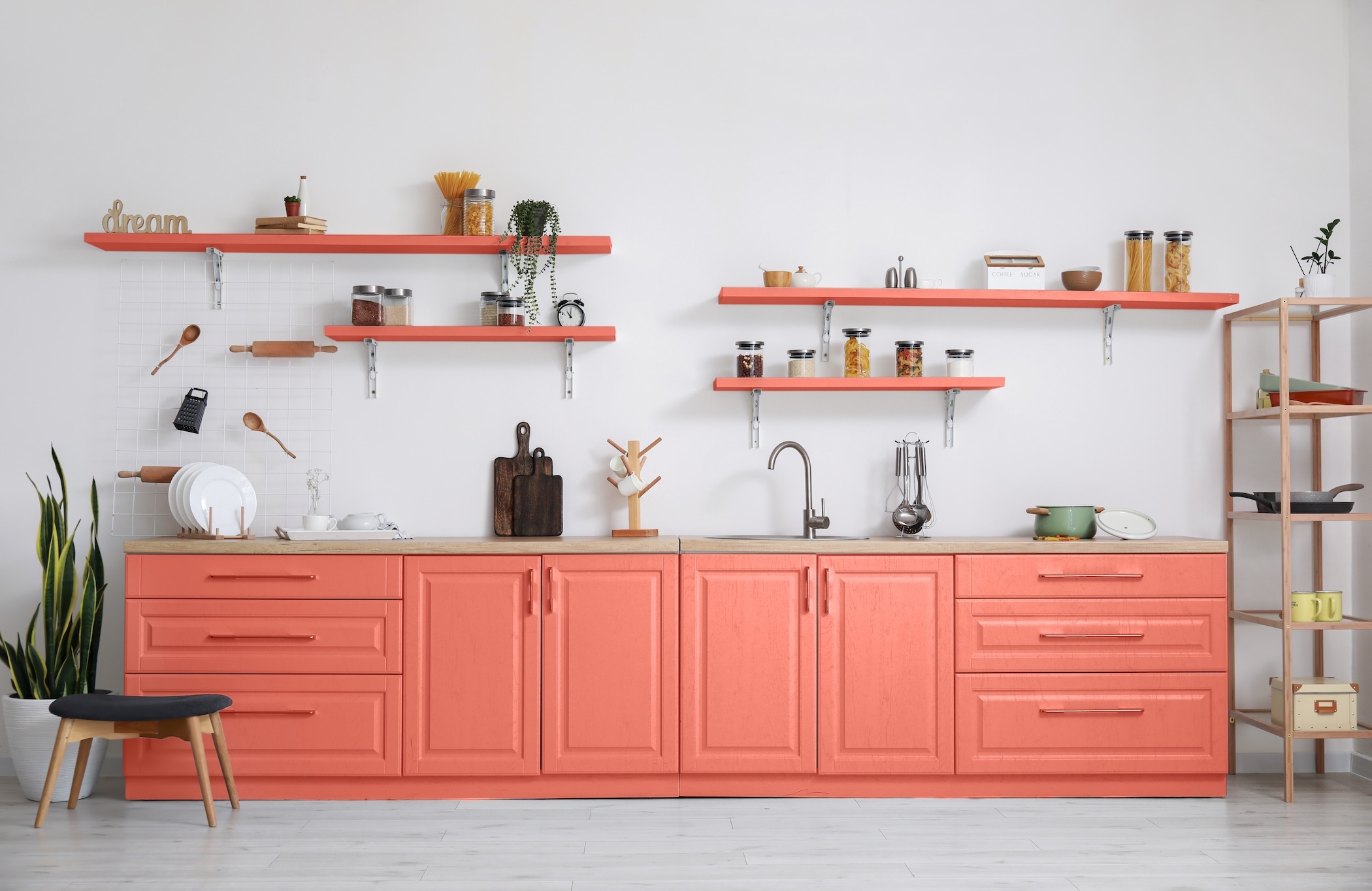 Interior of light kitchen with coral furniture and utensils