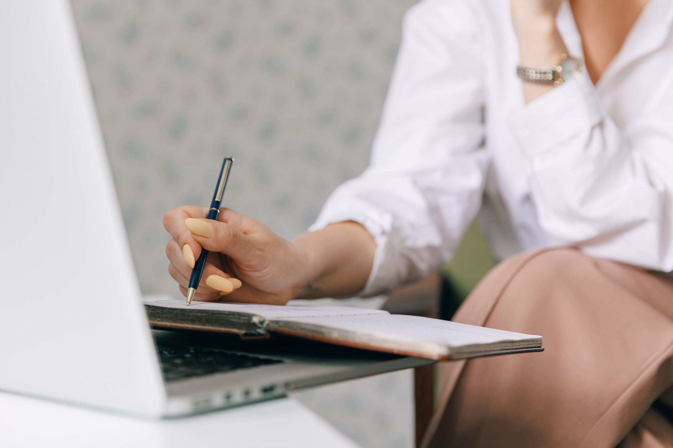 Closeup woman psychotherapist is holding notebook and making notes during online therapy session, background internet laptop with web call